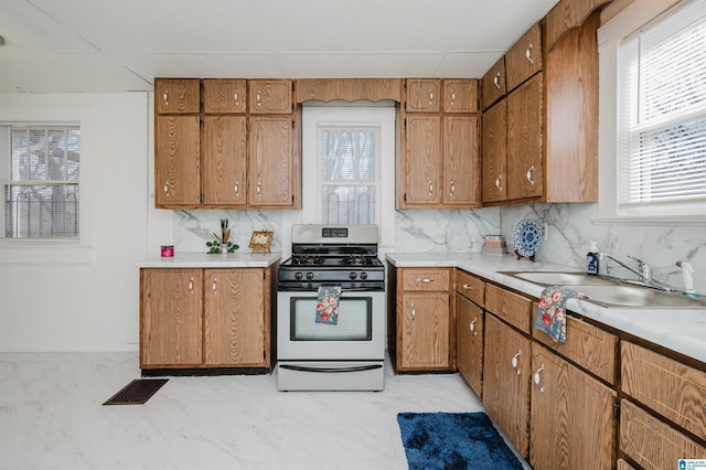 kitchen featuring visible vents, light countertops, a sink, and stainless steel gas range oven