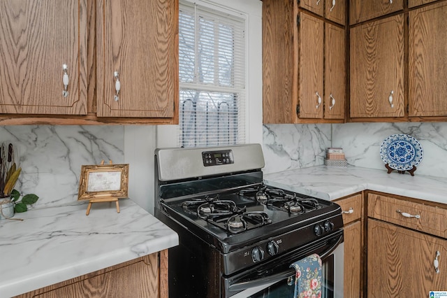 kitchen with brown cabinetry, light countertops, and stainless steel range with gas stovetop