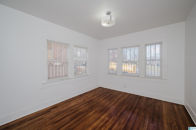 unfurnished room with dark wood-style flooring and baseboards