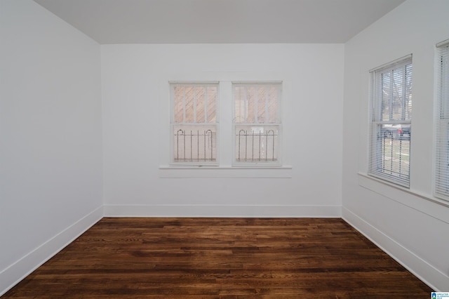 spare room with baseboards and dark wood finished floors