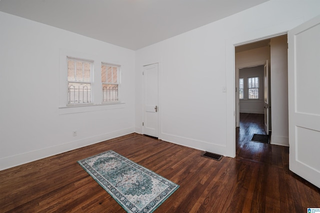 unfurnished room featuring visible vents, baseboards, and wood finished floors