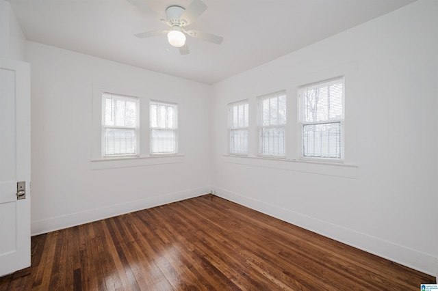 empty room featuring a healthy amount of sunlight, dark wood-style flooring, a ceiling fan, and baseboards