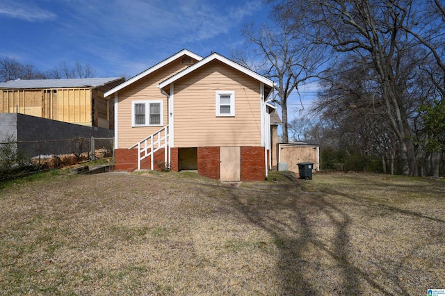 rear view of house featuring entry steps, brick siding, and a lawn