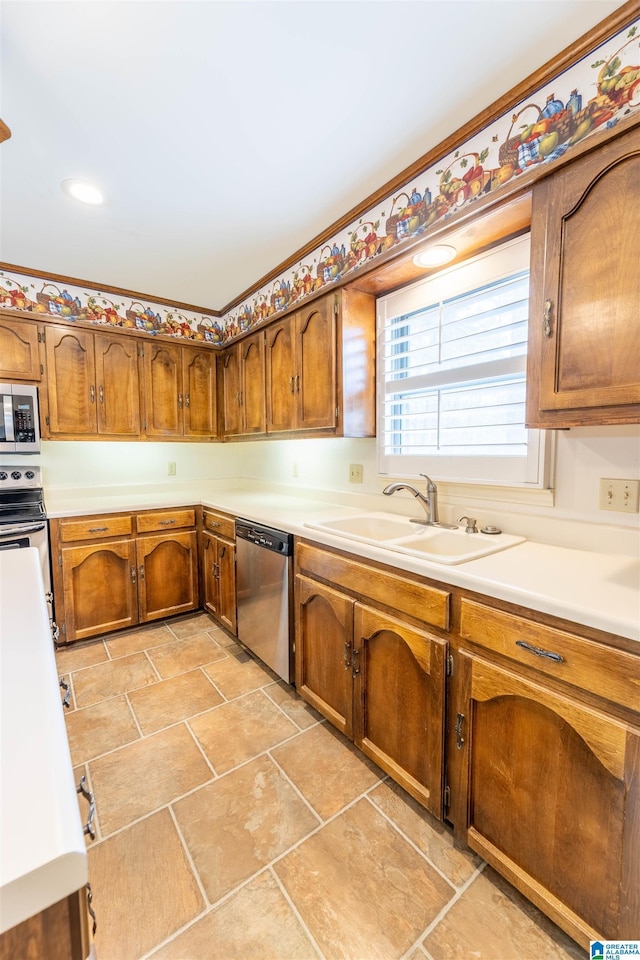 kitchen featuring stainless steel appliances, brown cabinetry, a sink, and light countertops