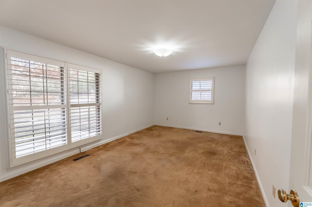 spare room with carpet floors, visible vents, and baseboards