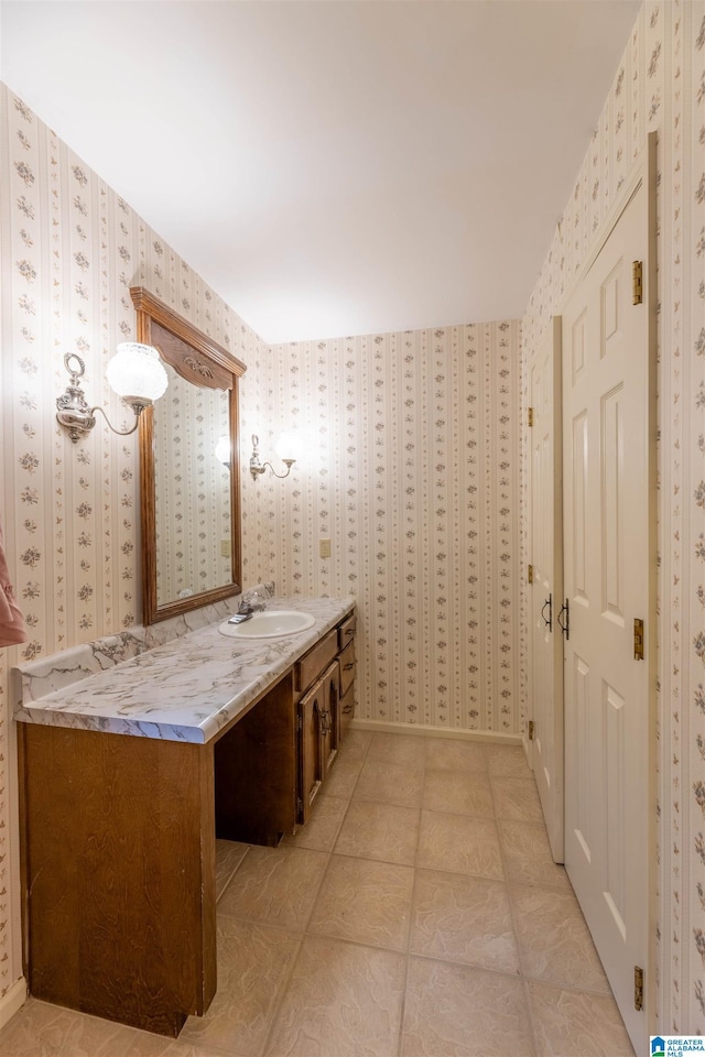 bathroom with wallpapered walls, tile patterned flooring, and vanity