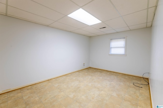 spare room featuring visible vents, a paneled ceiling, and baseboards