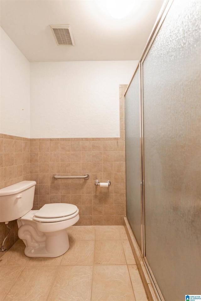 full bath featuring tile walls, visible vents, toilet, a shower stall, and tile patterned floors