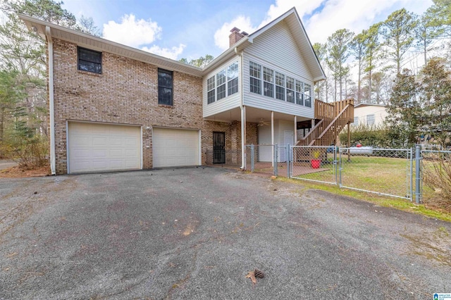 view of front of property with a chimney, stairway, aphalt driveway, a gate, and brick siding