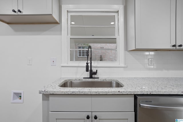 kitchen with a sink, light stone countertops, tasteful backsplash, and stainless steel dishwasher