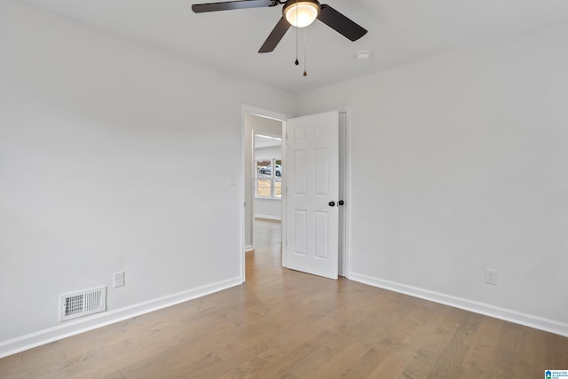 spare room featuring a ceiling fan, baseboards, visible vents, and wood finished floors