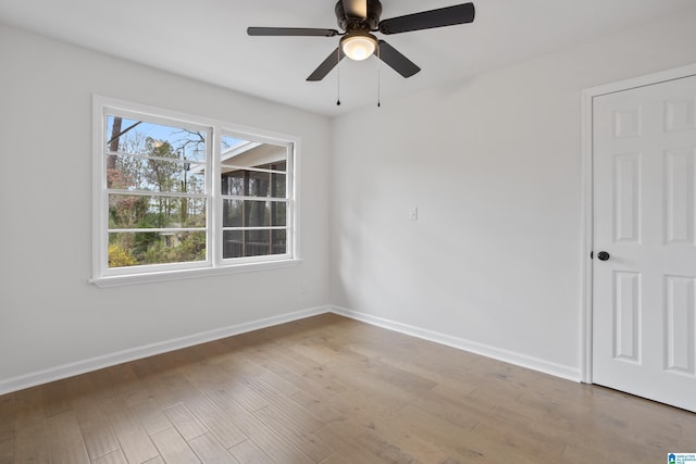 spare room featuring light wood finished floors, ceiling fan, and baseboards