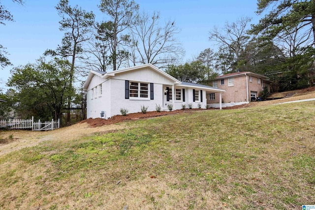 ranch-style house featuring a front yard, brick siding, and fence