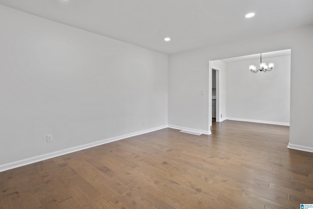 spare room featuring dark wood-style floors, baseboards, a notable chandelier, and recessed lighting