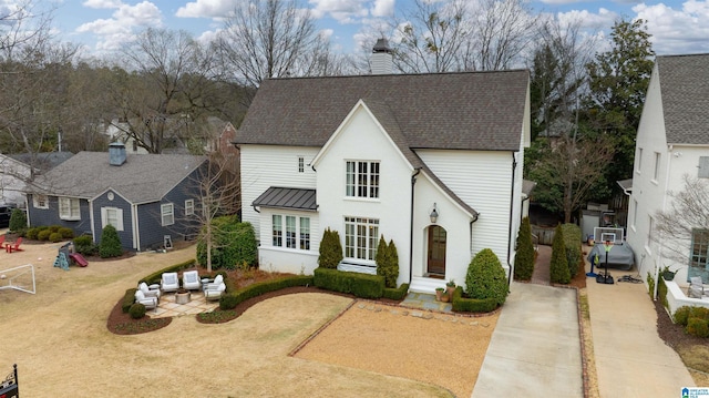 view of front of home with a patio area, driveway, a chimney, and a shingled roof