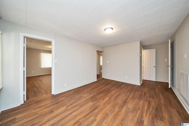 unfurnished room featuring wood finished floors, visible vents, and baseboards