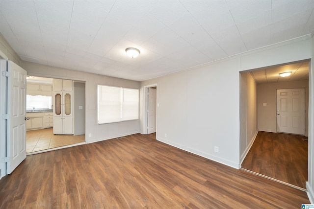 unfurnished bedroom featuring ensuite bath, baseboards, and wood finished floors