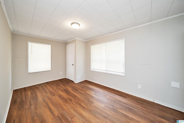 unfurnished room with dark wood-style floors, baseboards, visible vents, and crown molding