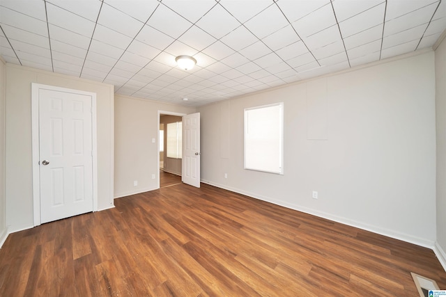 empty room featuring wood finished floors, visible vents, and baseboards