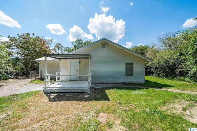 back of property with fence, a deck, and a lawn