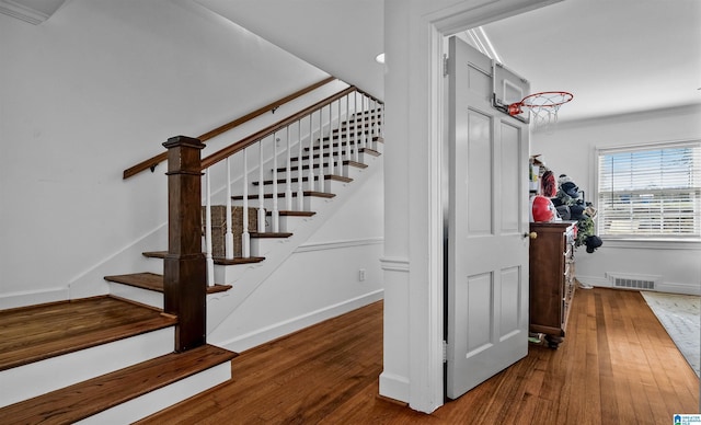 staircase featuring visible vents, ornamental molding, baseboards, and hardwood / wood-style flooring