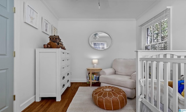 bedroom with baseboards, a nursery area, dark wood finished floors, and crown molding