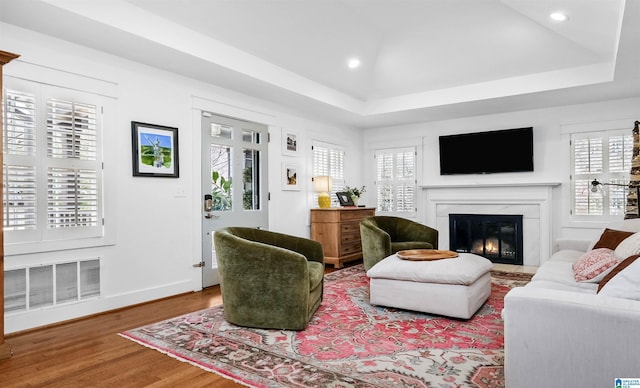 living room with wood finished floors, visible vents, a fireplace, recessed lighting, and a raised ceiling