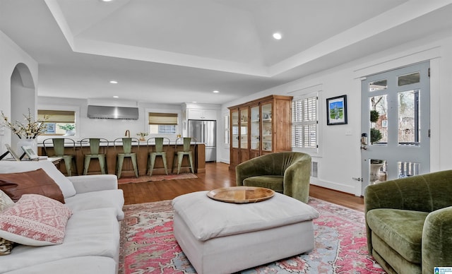 living room featuring recessed lighting, a tray ceiling, baseboards, and wood finished floors