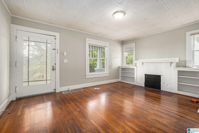 unfurnished living room with a brick fireplace, wood-type flooring, baseboards, and crown molding