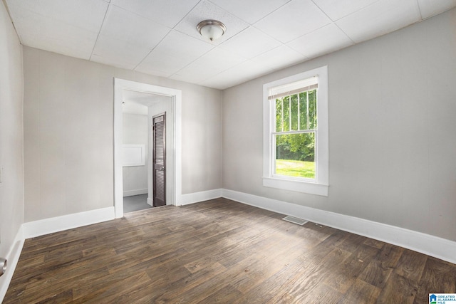 unfurnished room with dark wood-style flooring, visible vents, and baseboards