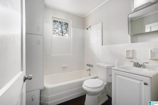 full bath featuring toilet, a wainscoted wall, shower / bath combination, vanity, and tile walls