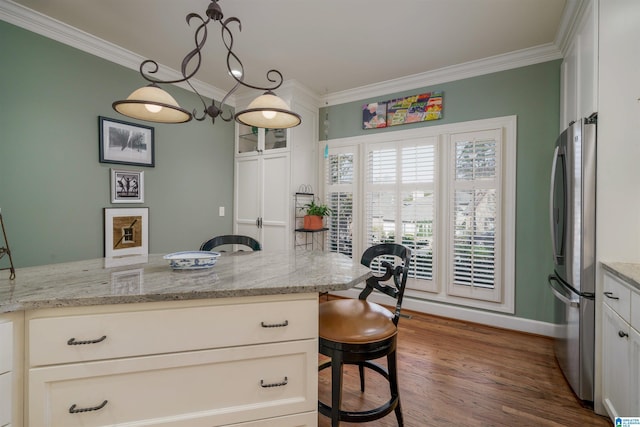 kitchen featuring ornamental molding, white cabinets, wood finished floors, and freestanding refrigerator