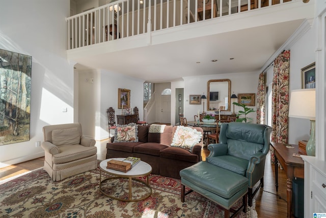 living room with wood finished floors, a towering ceiling, baseboards, stairway, and crown molding