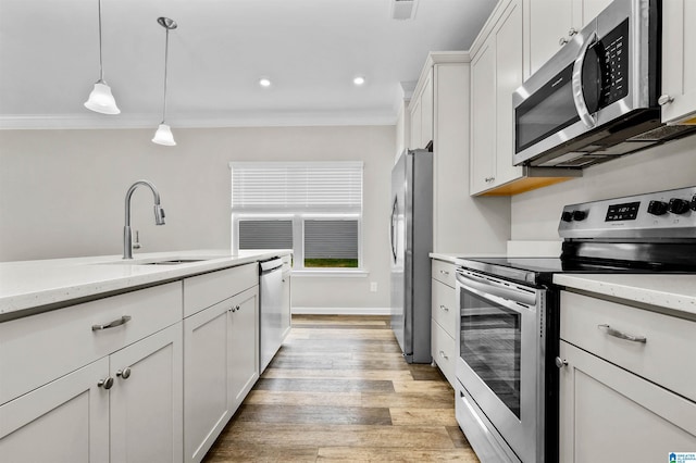 kitchen featuring decorative light fixtures, stainless steel appliances, ornamental molding, white cabinets, and a sink