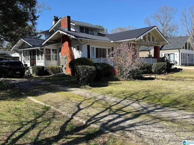 view of front facade with a front yard, metal roof, and a chimney