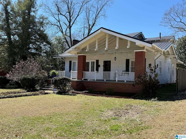 view of front of property with a chimney, covered porch, a standing seam roof, metal roof, and a front lawn