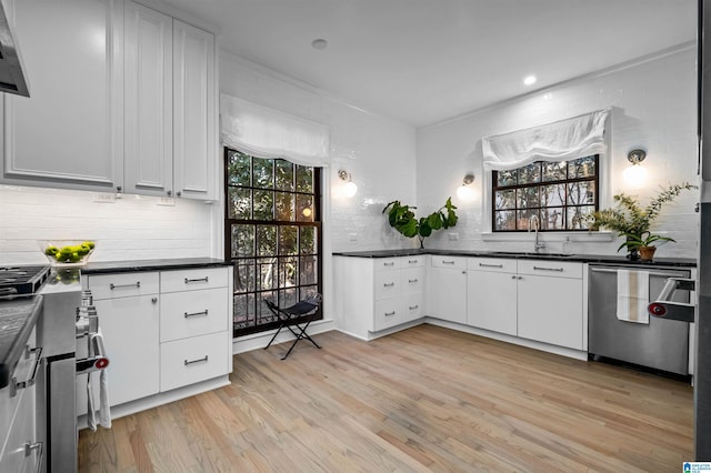 kitchen with dark countertops, a sink, light wood-type flooring, plenty of natural light, and dishwasher