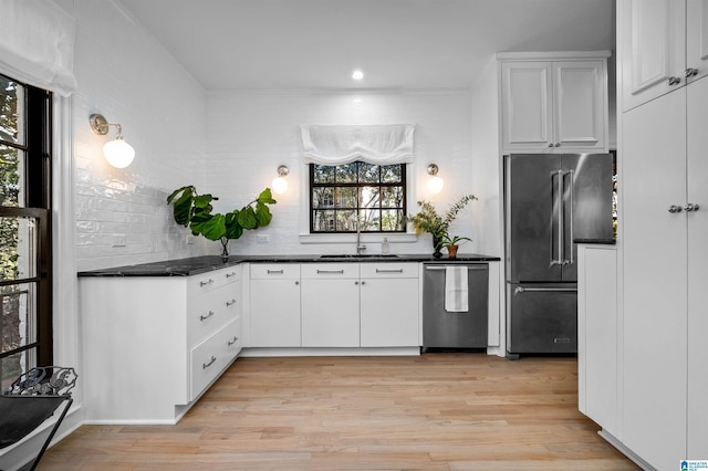 kitchen with dark countertops, light wood-type flooring, appliances with stainless steel finishes, and a sink