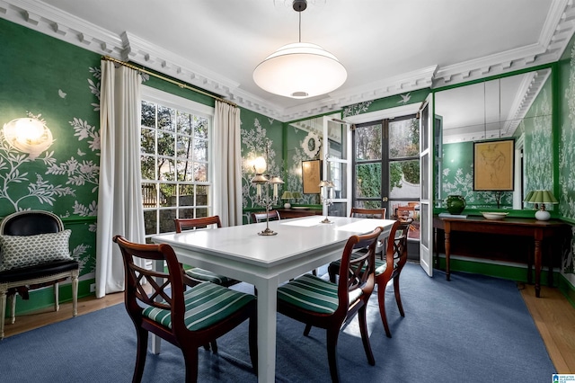 dining space featuring crown molding, baseboards, wood finished floors, and wallpapered walls