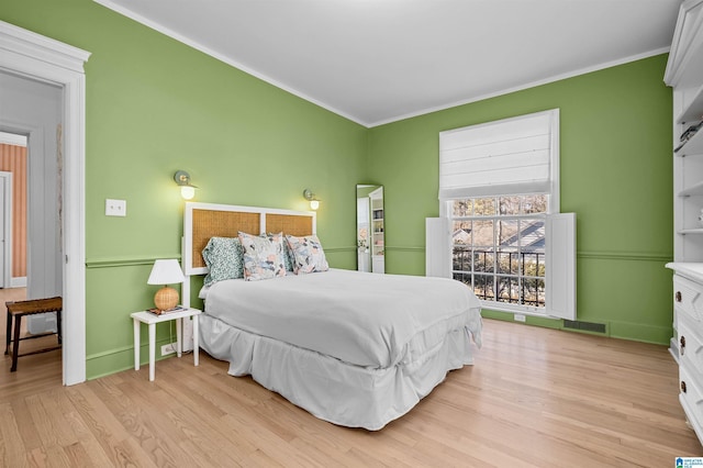 bedroom with visible vents, crown molding, and wood finished floors