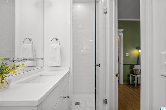 full bathroom featuring ornamental molding, wood finished floors, a shower stall, and vanity