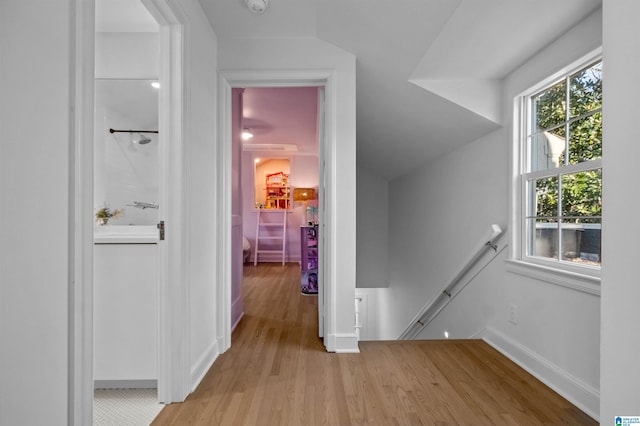 hallway featuring light wood finished floors, an upstairs landing, and baseboards