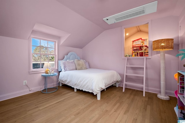 bedroom featuring baseboards, visible vents, vaulted ceiling, and wood finished floors