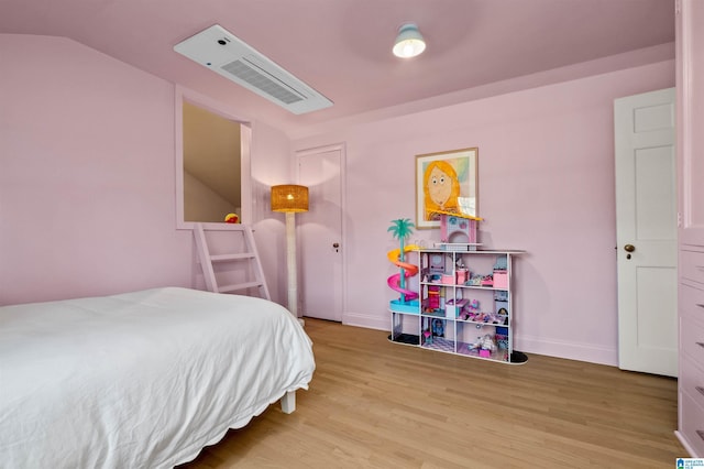 bedroom with vaulted ceiling, wood finished floors, visible vents, and baseboards