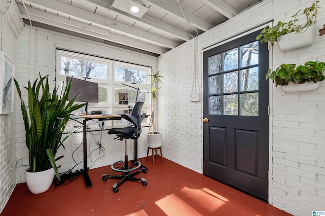 home office featuring finished concrete flooring and brick wall