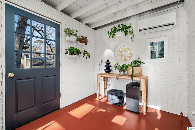 foyer entrance featuring finished concrete flooring, brick wall, beamed ceiling, and a wall unit AC