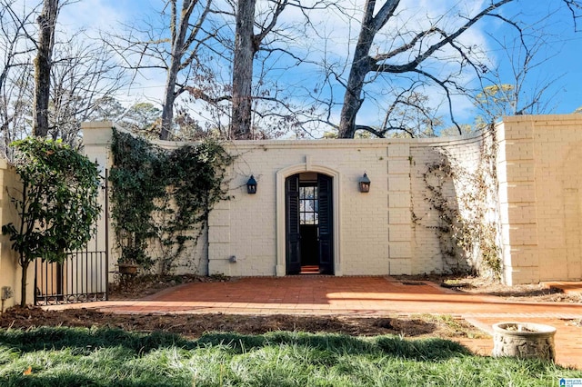 view of exterior entry with a patio and brick siding