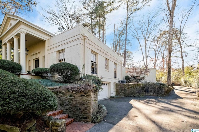 view of home's exterior with a garage, driveway, and cooling unit