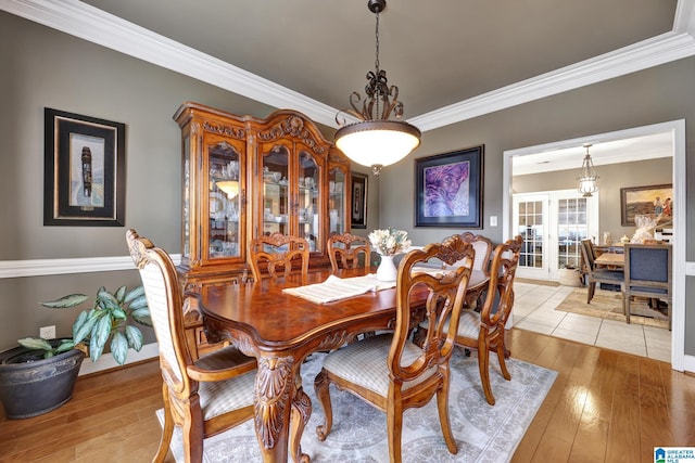 dining area with french doors, light wood-type flooring, and crown molding