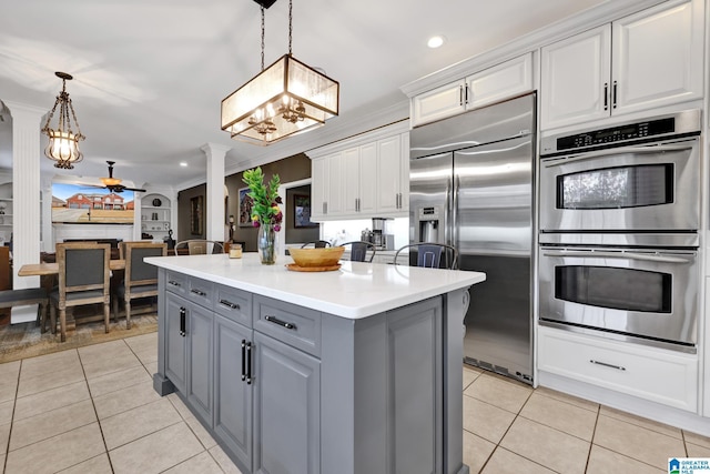 kitchen featuring light tile patterned flooring, gray cabinetry, stainless steel appliances, a ceiling fan, and ornate columns